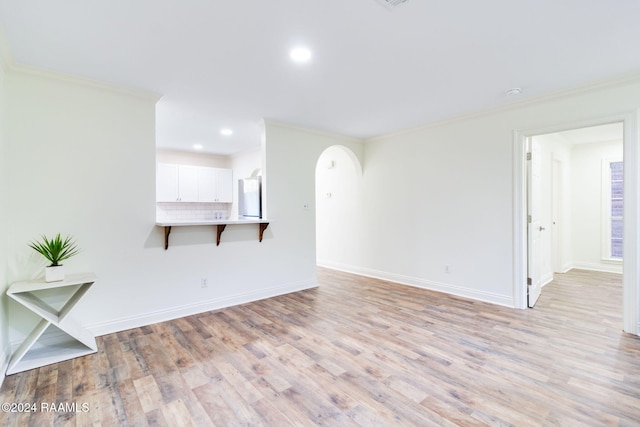 empty room featuring crown molding, light hardwood / wood-style flooring, and a healthy amount of sunlight