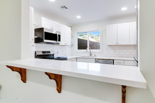 kitchen featuring appliances with stainless steel finishes, white cabinetry, a kitchen breakfast bar, and sink