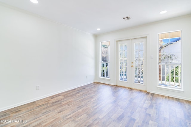 spare room featuring crown molding, light hardwood / wood-style flooring, and french doors