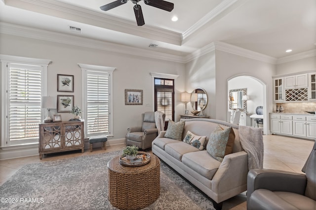 tiled living room featuring ornamental molding, a tray ceiling, and ceiling fan