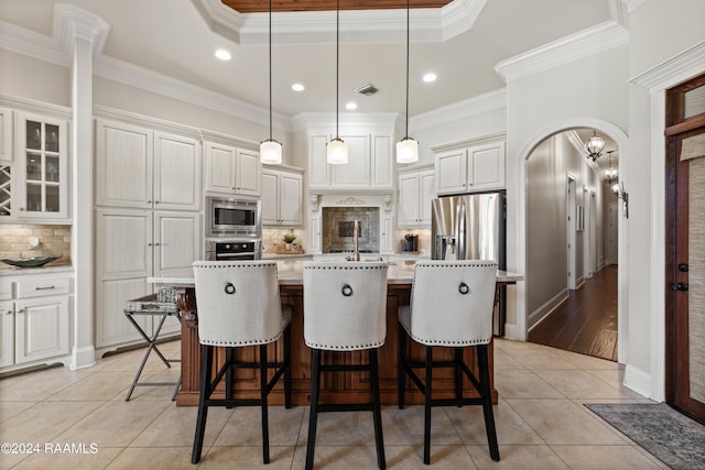 kitchen featuring stainless steel appliances, a center island with sink, ornamental molding, light tile patterned flooring, and decorative light fixtures