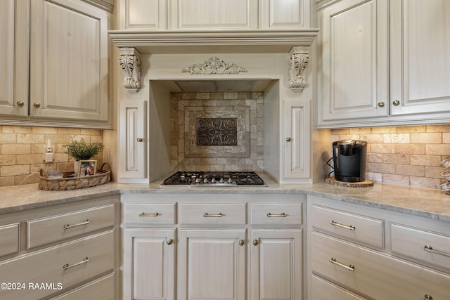 kitchen with decorative backsplash, light stone countertops, and stainless steel gas cooktop