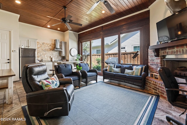 living room with ceiling fan, wooden ceiling, ornamental molding, and a brick fireplace