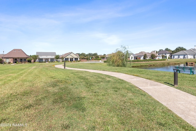 view of property's community with a water view and a lawn