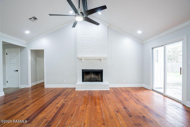 unfurnished living room featuring a brick fireplace, lofted ceiling, hardwood / wood-style flooring, ornamental molding, and ceiling fan