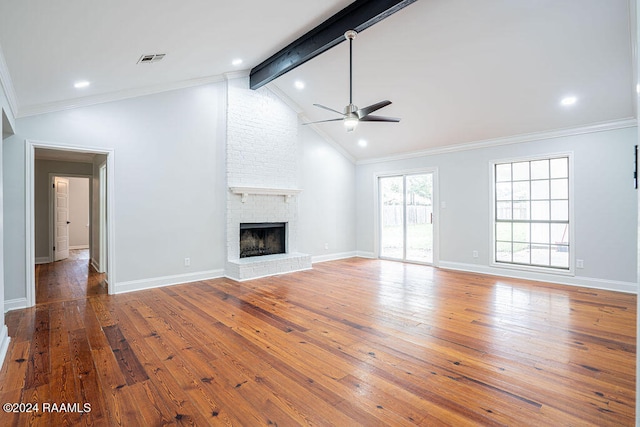 unfurnished living room with wood-type flooring, ornamental molding, vaulted ceiling with beams, a fireplace, and ceiling fan