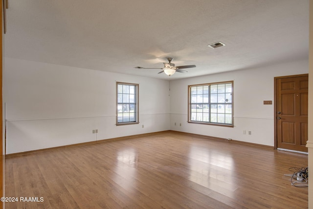 empty room with ceiling fan, light hardwood / wood-style floors, and a wealth of natural light