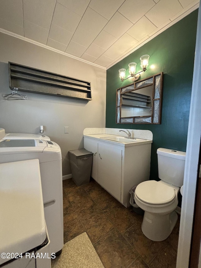 bathroom with crown molding, vanity, washing machine and clothes dryer, and toilet