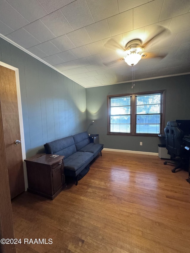 living room with wood-type flooring, crown molding, and ceiling fan