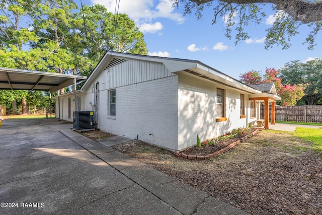 view of side of home with central air condition unit and a carport