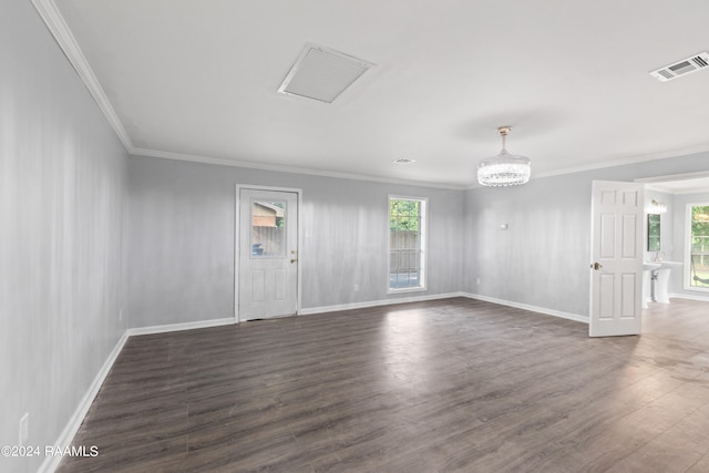 empty room with a notable chandelier, dark hardwood / wood-style floors, and crown molding