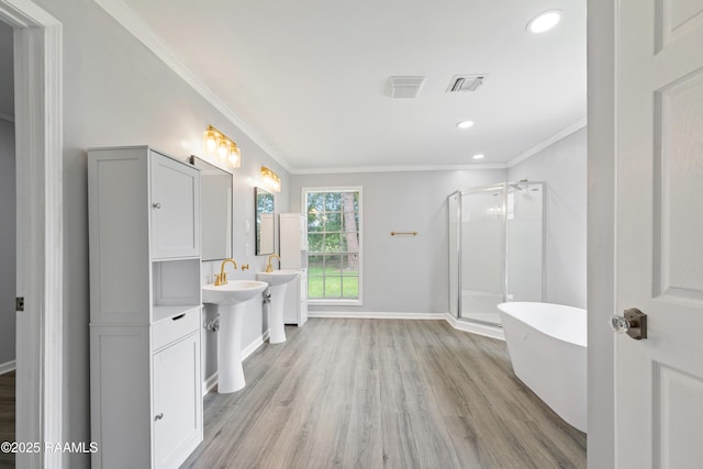 406 Orange Grove Ave, New Iberia, LA 70560 - bathroom featuring ornamental molding, wood finished floors, a stall shower, a freestanding tub, and baseboards