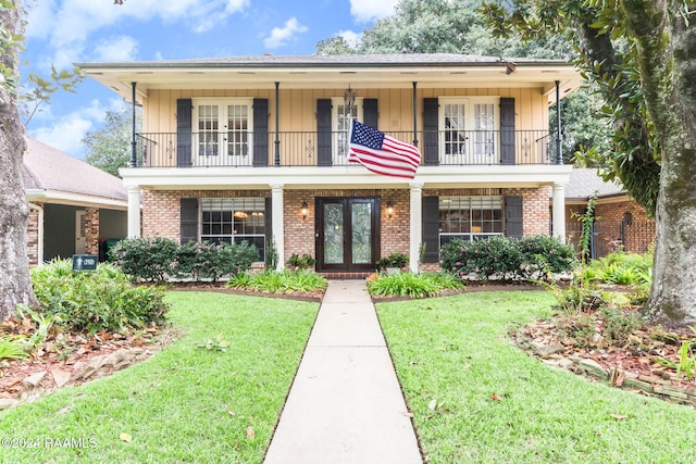 view of front facade featuring french doors, a front yard, and a balcony