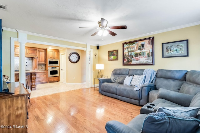 living room with ceiling fan, ornate columns, crown molding, and light hardwood / wood-style flooring