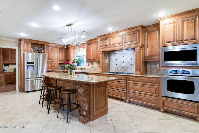 kitchen featuring a center island, crown molding, light stone countertops, pendant lighting, and appliances with stainless steel finishes