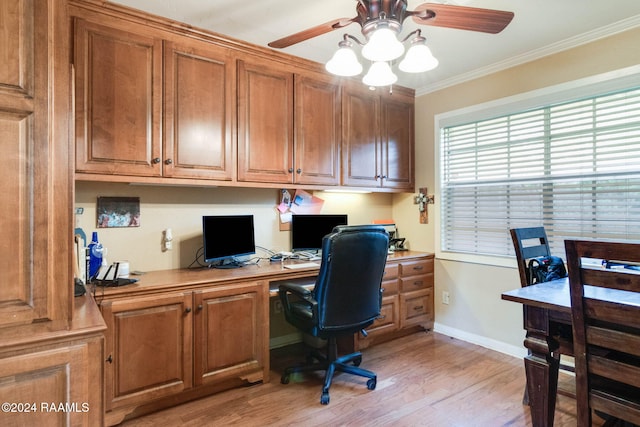 home office with built in desk, ceiling fan, light hardwood / wood-style flooring, and ornamental molding