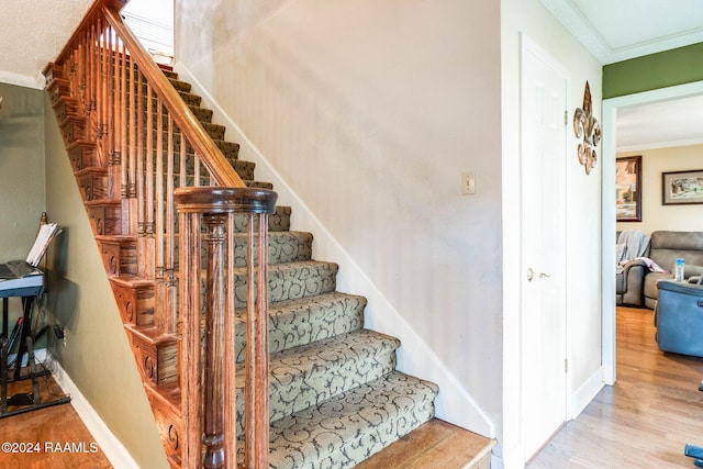 stairs with ornamental molding and hardwood / wood-style flooring