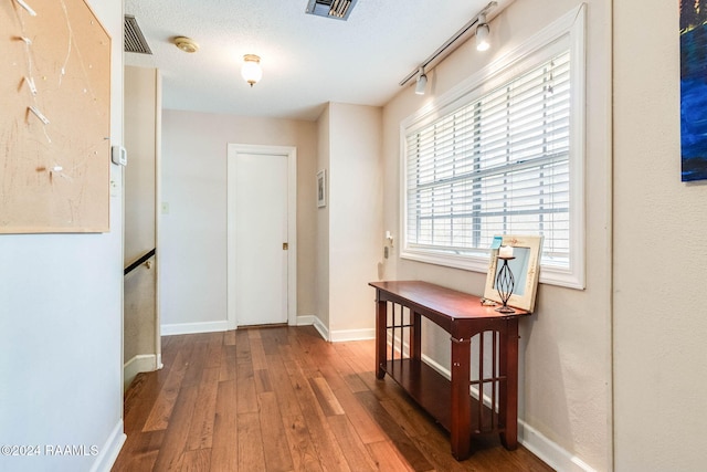 hallway featuring wood-type flooring, a textured ceiling, and track lighting