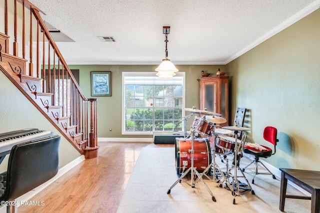 dining space featuring a textured ceiling, light hardwood / wood-style floors, and crown molding