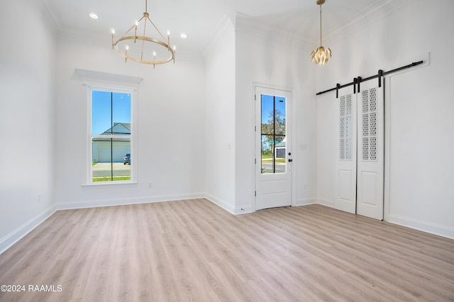 interior space featuring an inviting chandelier, a healthy amount of sunlight, a barn door, and light wood-type flooring