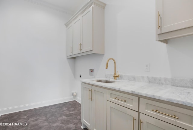 kitchen featuring white cabinetry, sink, crown molding, and light stone countertops