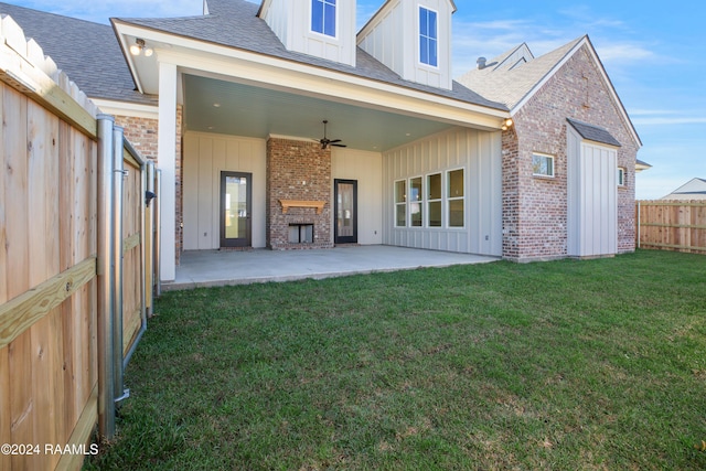 rear view of house with ceiling fan, a fireplace, a patio area, and a lawn