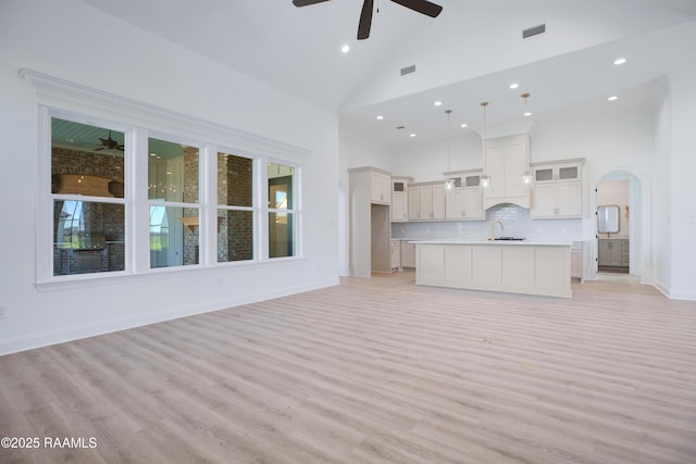 unfurnished living room featuring ceiling fan, sink, high vaulted ceiling, and light hardwood / wood-style flooring