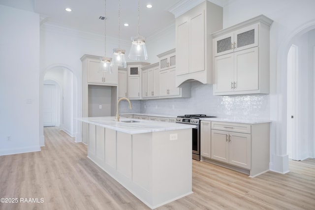 kitchen with white cabinets, pendant lighting, a center island with sink, and stainless steel gas range