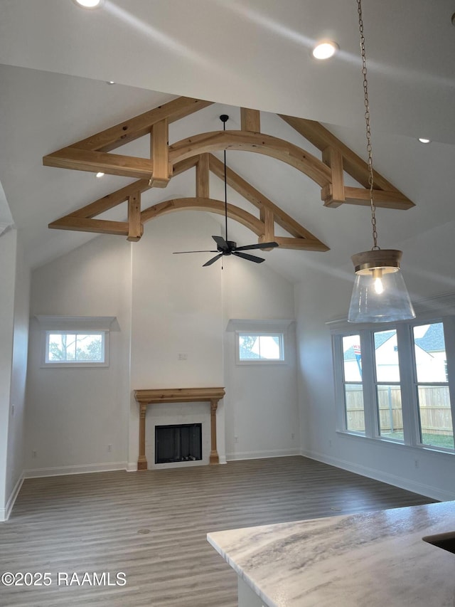 unfurnished living room with hardwood / wood-style flooring, ceiling fan, beam ceiling, and high vaulted ceiling