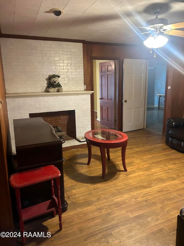 sitting room with a fireplace, ceiling fan, crown molding, and hardwood / wood-style flooring