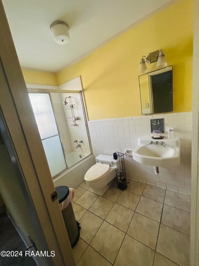 full bathroom featuring sink, tile patterned floors, toilet, shower / bath combination with glass door, and tile walls