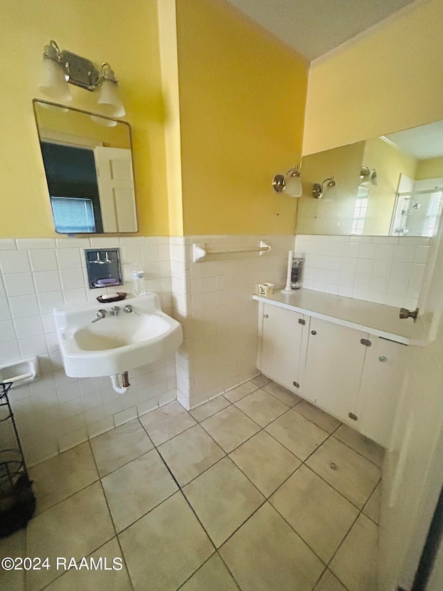 bathroom with tile patterned flooring, plenty of natural light, sink, and tile walls