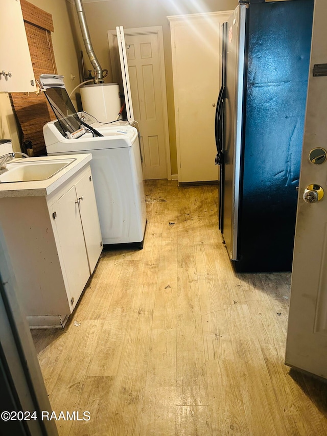 laundry area featuring light hardwood / wood-style flooring, cabinets, gas water heater, and washer / dryer