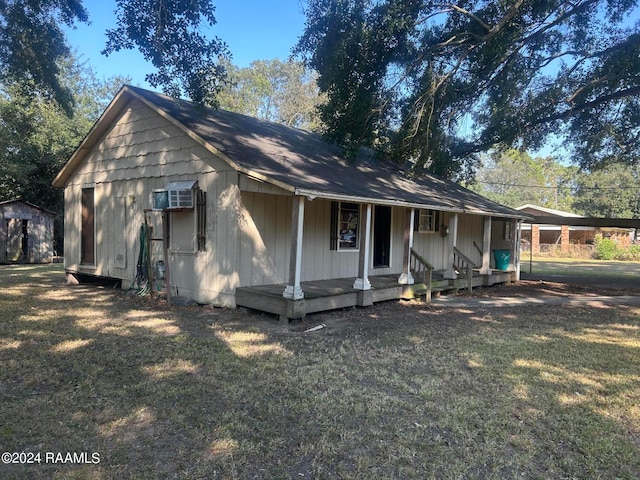 view of front of home featuring a front yard, covered porch, and a storage unit