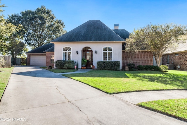 view of front of property with a front lawn, central AC unit, and a garage