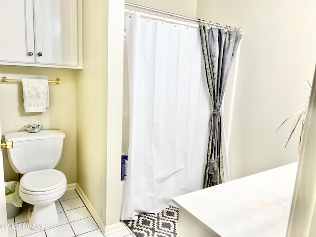 bathroom featuring toilet, curtained shower, and tile patterned flooring