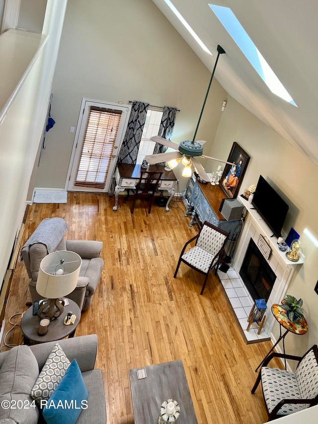 living room featuring a skylight, hardwood / wood-style floors, high vaulted ceiling, and a fireplace