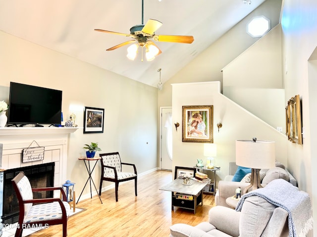 living room featuring a tile fireplace, high vaulted ceiling, light wood-type flooring, and ceiling fan