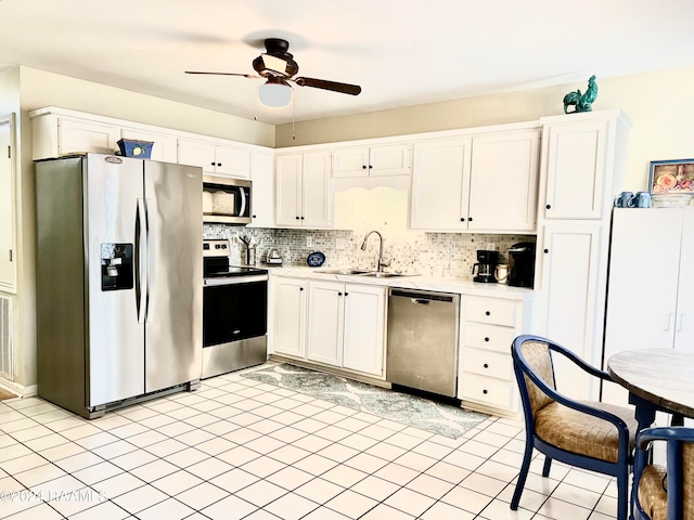 kitchen with appliances with stainless steel finishes, sink, white cabinetry, decorative backsplash, and light tile patterned floors