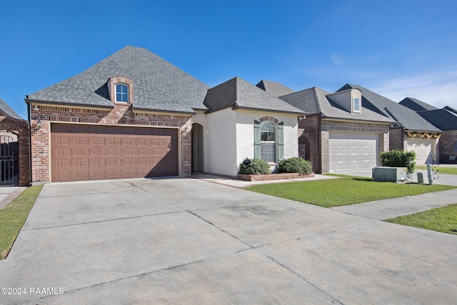 french provincial home featuring a front lawn and a garage