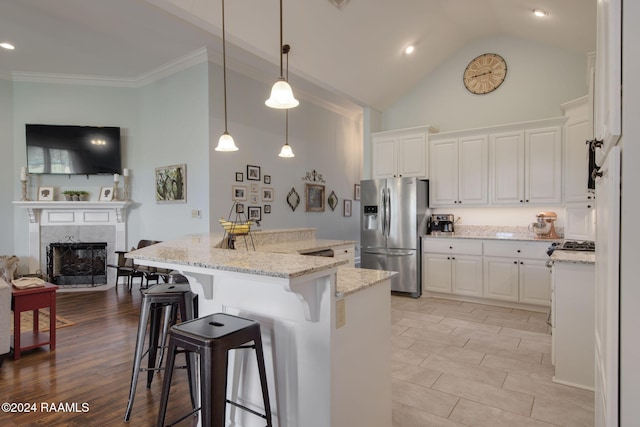 kitchen featuring stainless steel fridge, a breakfast bar area, a center island with sink, white cabinets, and light wood-type flooring