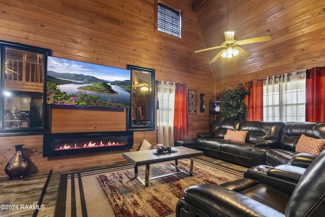 living room with hardwood / wood-style floors, ceiling fan, wood walls, and high vaulted ceiling