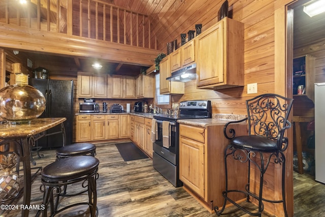 kitchen with wood walls, dark wood-type flooring, black appliances, sink, and light brown cabinetry