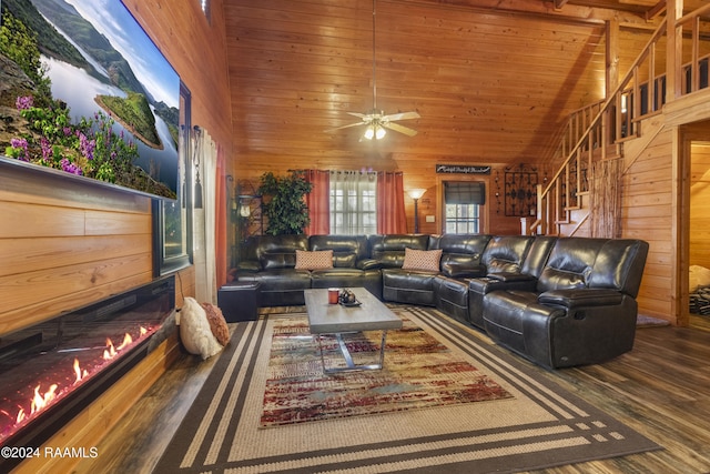 living room with hardwood / wood-style flooring, high vaulted ceiling, ceiling fan, and wood walls