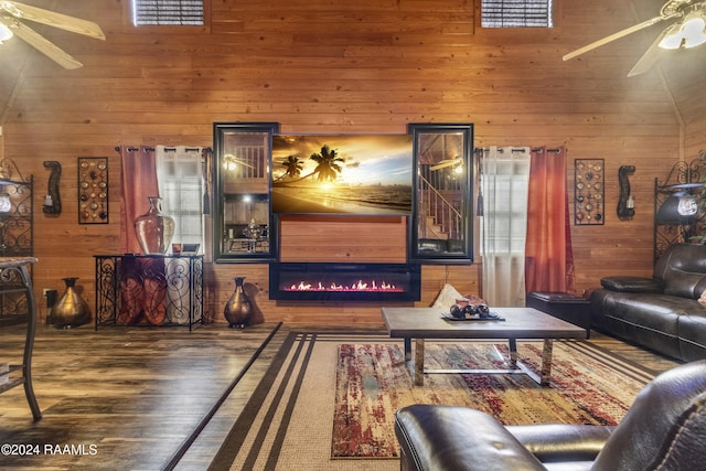 living room with hardwood / wood-style floors, high vaulted ceiling, and wood walls