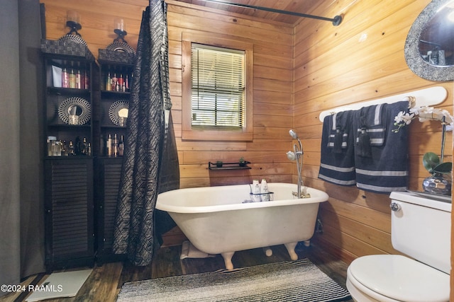 bathroom featuring a washtub, hardwood / wood-style floors, toilet, and wood walls