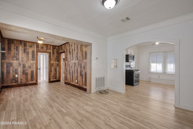 unfurnished living room featuring ceiling fan, light wood-type flooring, wooden walls, and crown molding