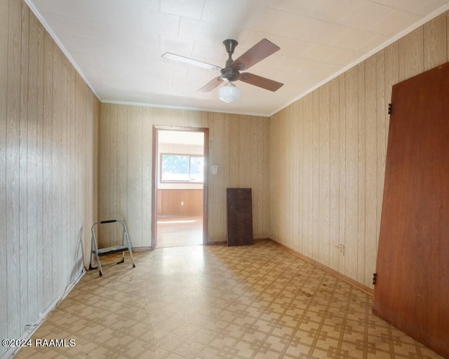 unfurnished room with ornamental molding, ceiling fan, and wood walls