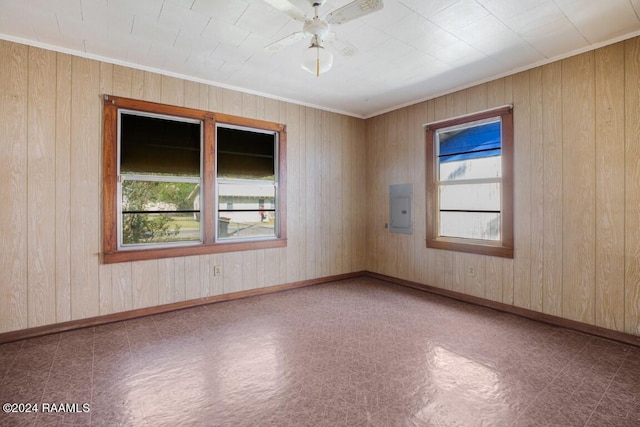 empty room with ceiling fan, electric panel, and wood walls