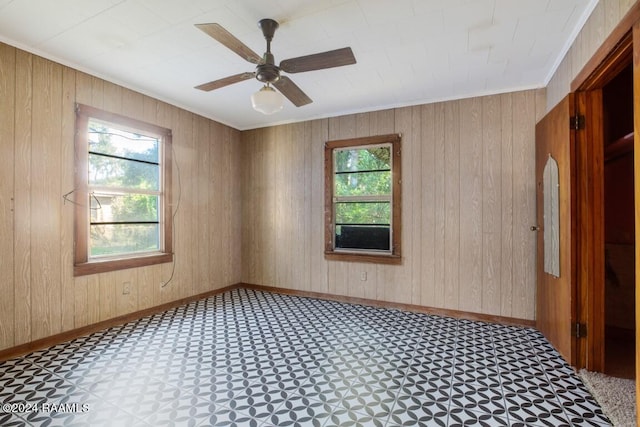 empty room featuring ceiling fan and wood walls